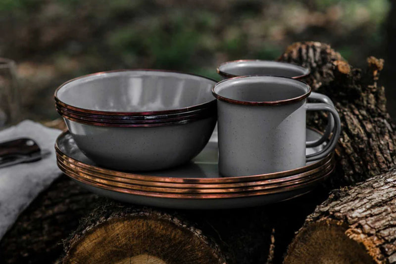 Enamelware set with bowl and mugs on a wooden surface outdoors
