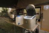 Camper van interior with a pot, water containers, and ice maker on a table.